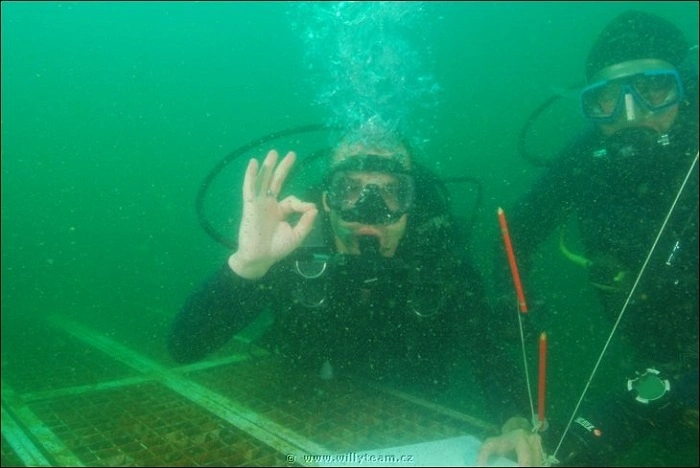 Dva potápěči při hledání podvodní T5 keše – extrémní geocachingový zážitek pod hladinou jezera.