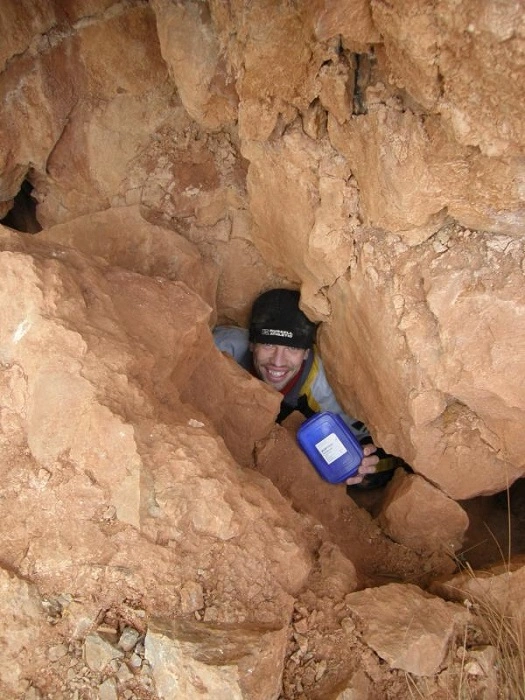 Geocacher při nalezení keše ukryté hluboko v jeskyni mezi kameny během T5 geocachingové výzvy.