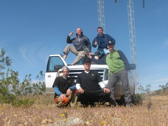 Skupina geokačerů pózuje u auta během lovu keší v USA – dobrodružství, týmová spolupráce a rozdíly mezi geocachingem v Americe a Evropě.