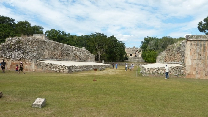 Hřiště na mayskou míčovou hru tlachtli v Uxmalu, obklopené kamennými zdmi a zelení.