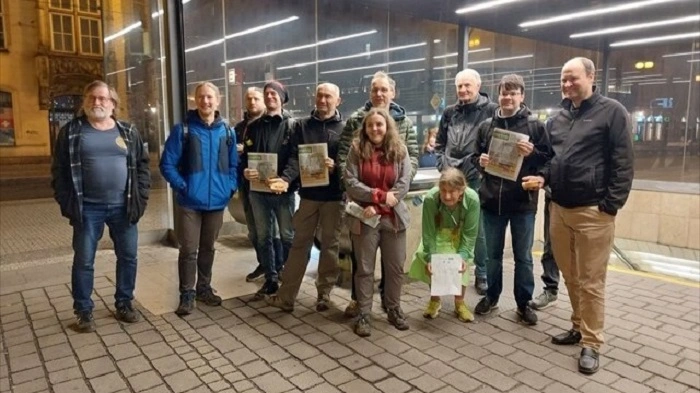 Skupina geokačerů pózuje před vchodem do stanice metra po skončení eventu zaměřeného na distribuci novin Metro.