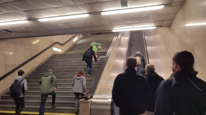 Účastníci geocachingového eventu vybíhají schody pražského metra během netradiční distribuce novin Metro.