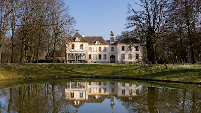 Historická stavba v Bronckhorstu odrážející se v klidné hladině rybníka, typická atmosféra nizozemského venkova.