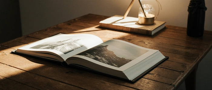 Otevřené fotoalbum na dřevěném stole zalité teplým světlem – symbol geokačerských vzpomínek a příběhů, které tvoří funkce Extremes by area v Project-GC.