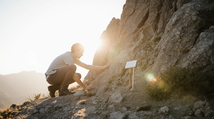 Geokačer nebo geolog zapisuje poznámky a fotí skalní útvar při přípravě nové Earthcache.