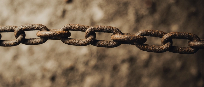 Detail rezavého železného řetězu, ilustrační foto k pravidlům geocachingu o řetězení eventů.