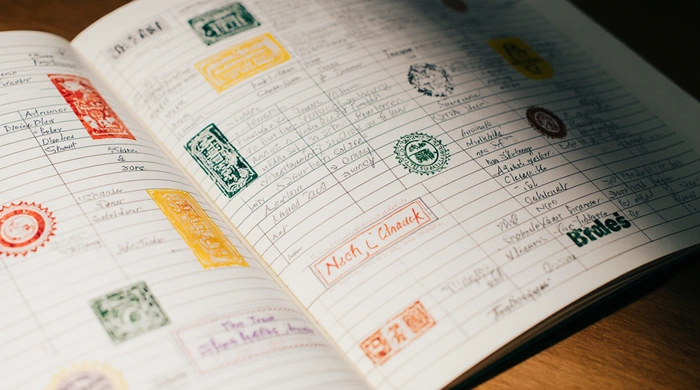 Otevřený logbook s barevnými otisky razítek od různých geokačerů, symbol radosti a sdílených zážitků z letterbox keší.