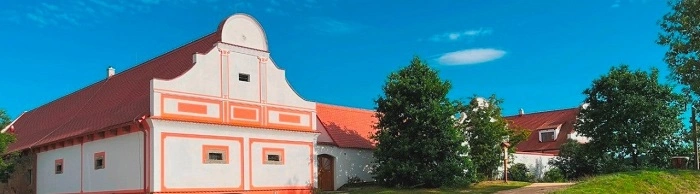 Historické budovy Barokního dvora Borotín v letním dni, klidné prostředí a útulná atmosféra místa, kde se návštěvníci geocachingového eventu cítí jako doma.