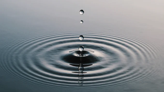Kapky vody vytvářející kruhy na klidné hladině – symbol rovnováhy a hydratace při geocachingu - voda na výletě