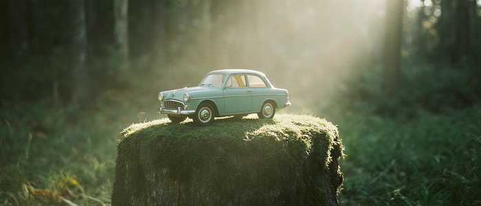 Malé dětské autíčko položené na pařezu v lese jako symbol klasické hračky v geocachingu