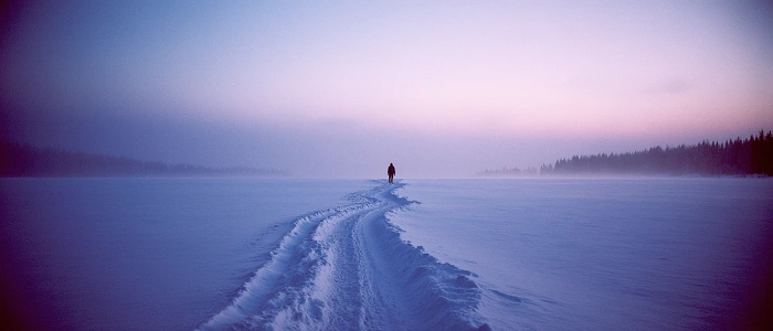 Osamělá stopa ve sněhu vedoucí zimní krajinou jako symbol rozloučení s geocachingovým rokem 2026