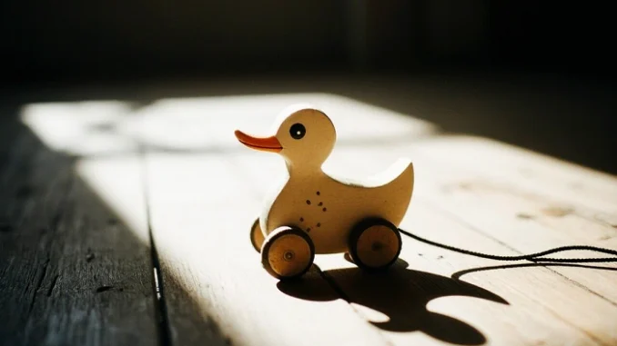 Dřevěná tahací kačenka na kolečkách jako symbol klasické hračky v geocachingu