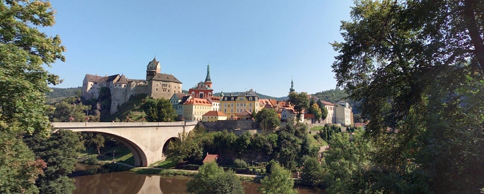 Panoramatický pohled na hrad Loket a most nad řekou Ohře, jasný den.