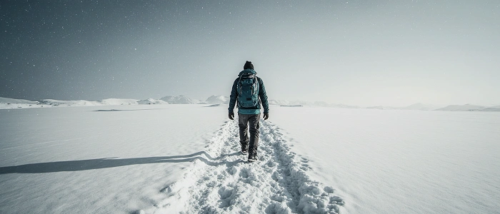 Postava kráčející zasněženou krajinou symbolizující nový začátek a motivaci k novoročním předsevzetím v geocachingu