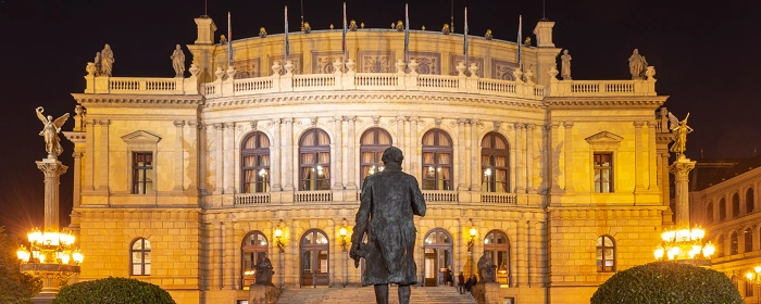 Noční pohled na Rudolfinum v Praze se sochou Antonína Dvořáka v popředí.