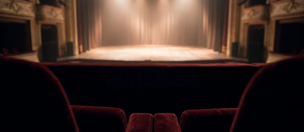 divadelní jeviště s oponou pohled z hlediště prázdné sedačky